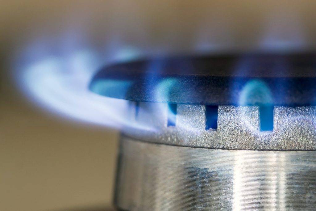 The even blue flames of a lit gas burner, close up.
