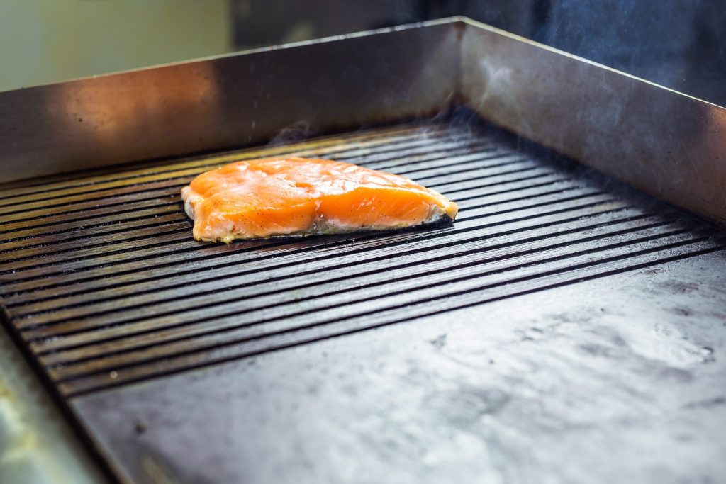 A fillet cooking on the grates of a built-in grill module set into a kitchen worktop