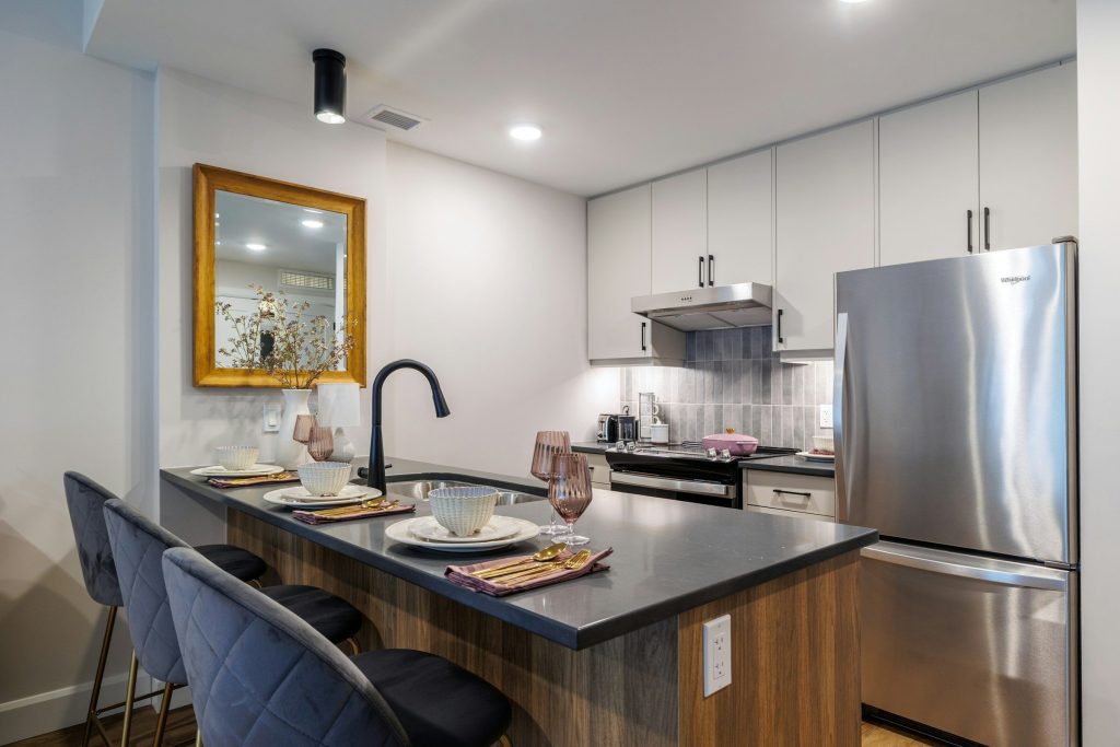 A kitchen island with stools in front of a tall built-in refrigerator in a run of cabinetry