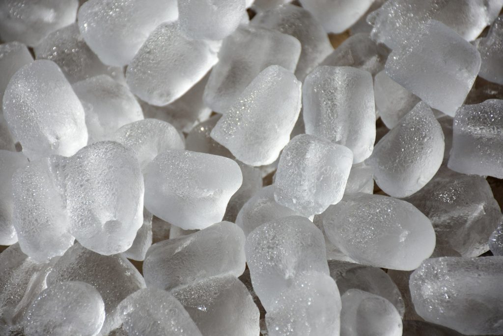 A close heap of machine-made ice cubes, wet at the edges