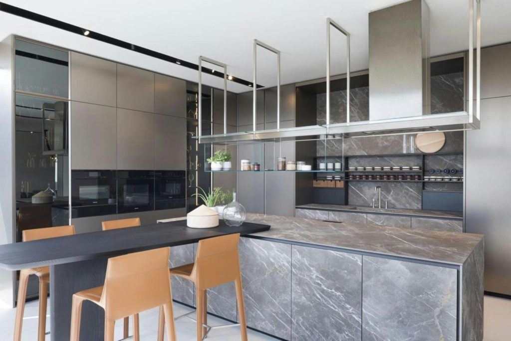 A kitchen island and stools in front of a run of cabinetry with integrated appliances