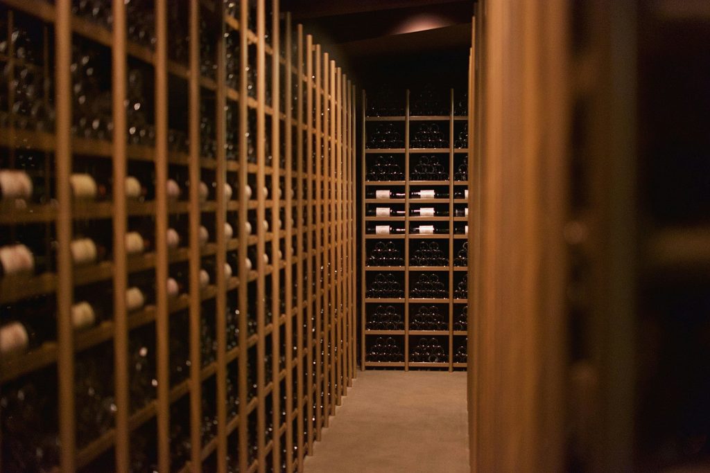 Rows of bottles on the wooden racks of a lit wine store