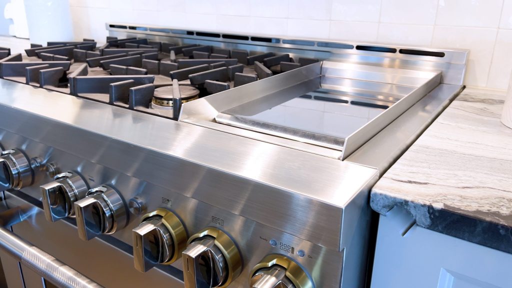 A stainless professional rangetop with a griddle plate, seen along the front edge