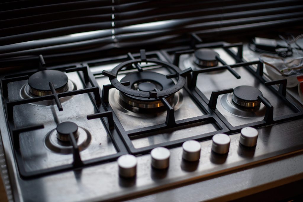 A five-burner gas deck seen along the cast grates, control knobs at the front edge
