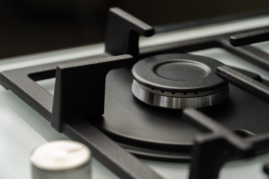 A gas burner and its cast grate, close up on a dark cooktop