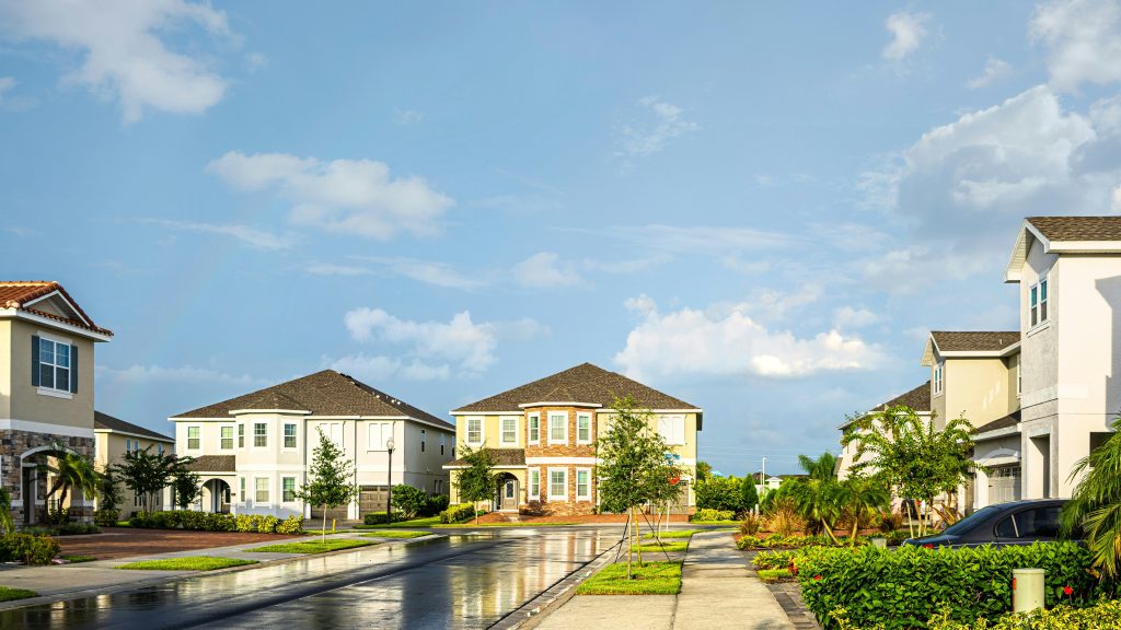 A street of newly built houses after rain, with palms in the front yards