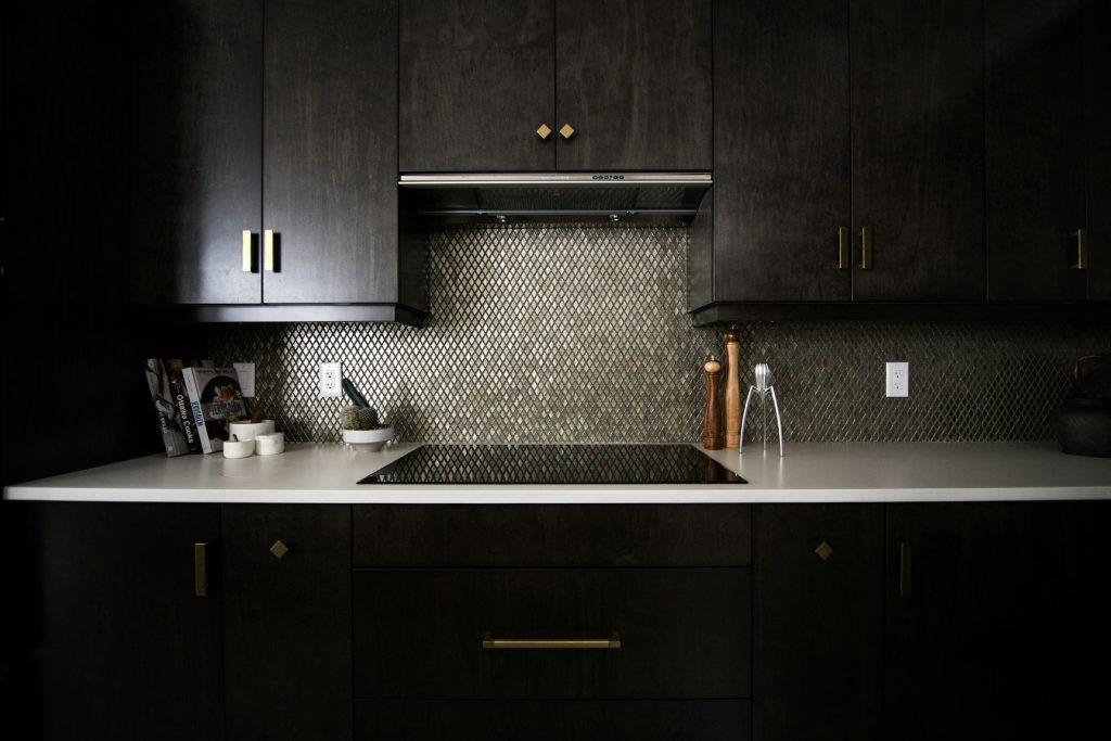 A dark kitchen with an induction hob set into a pale counter under a slim hood