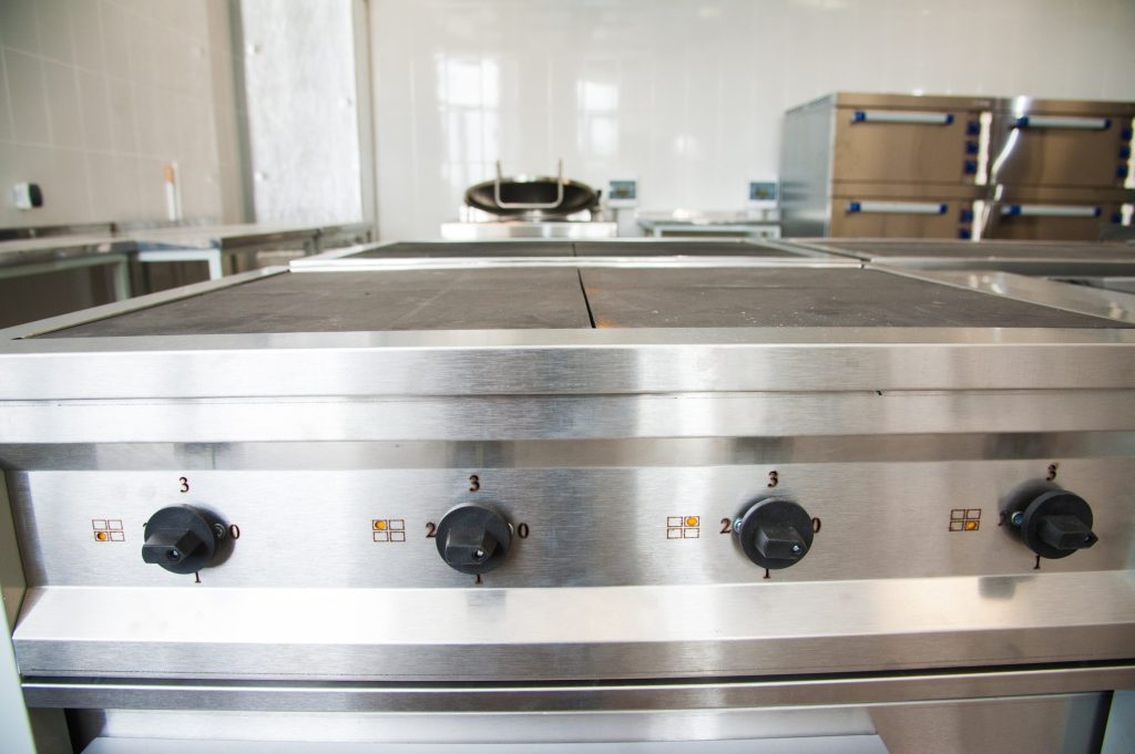 A wide stainless griddle plate with control knobs along the rail below it