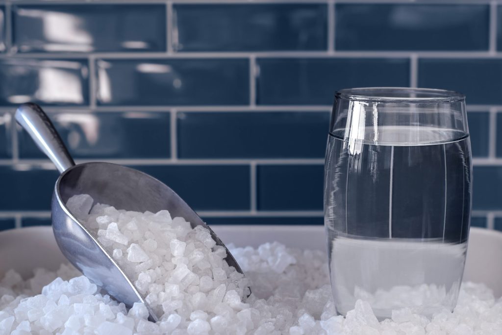 A scoop resting in crushed ice beside a glass of clear water