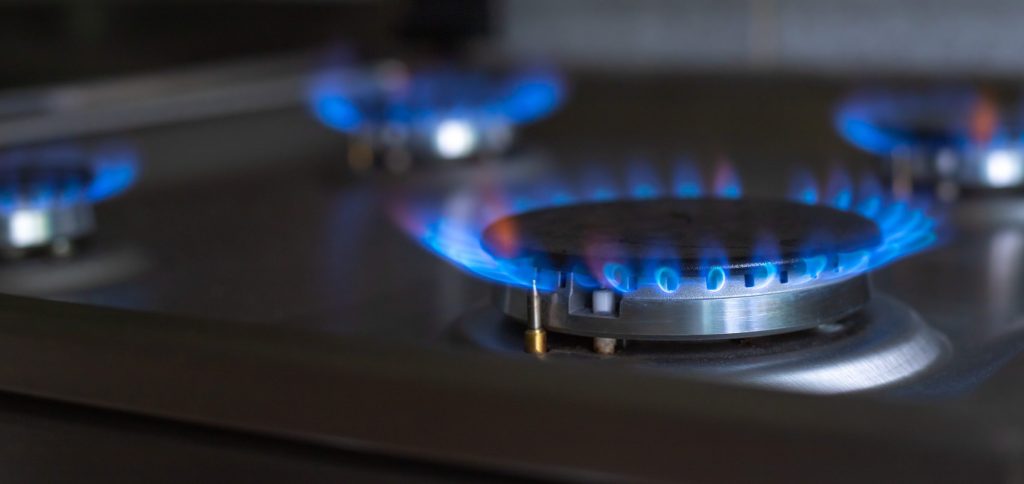 Two gas burners alight in a dark surround, the flame ring even and blue