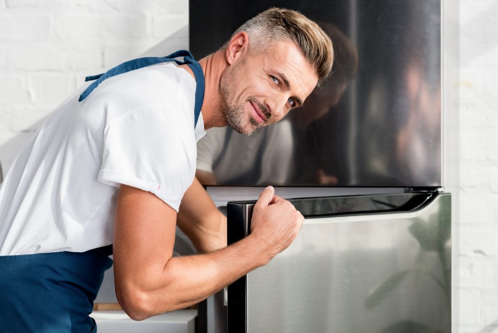 A technician working at the open door of a built-in refrigerator