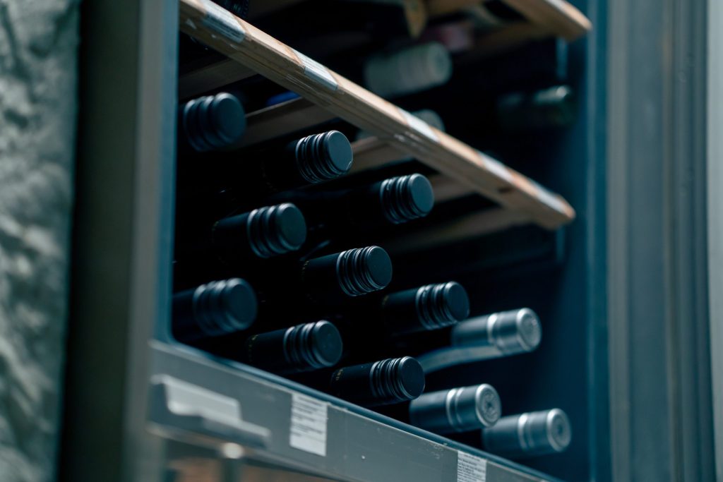 Bottles resting on the wooden racks of a cooled wine cabinet
