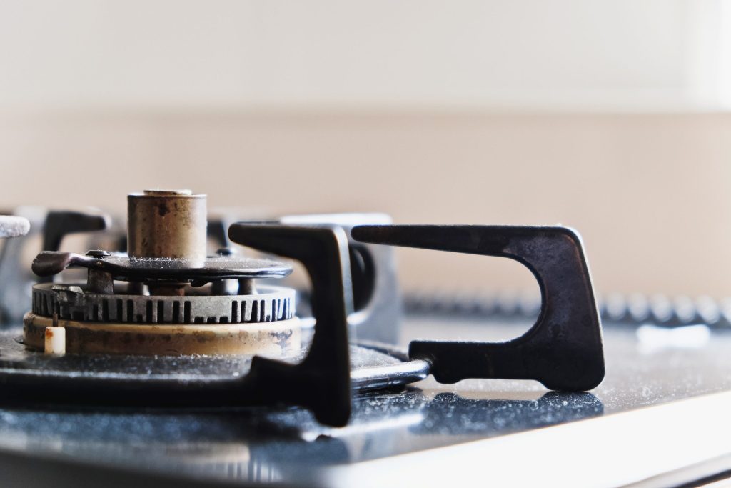 A gas burner cap lifted clear of its base on a cooktop, the igniter exposed