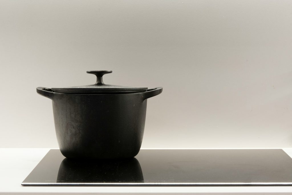 A black cast-iron casserole standing on a smooth induction surface
