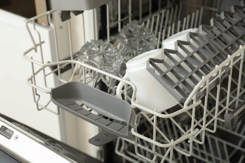 The lower basket and tub floor of an open dishwasher, empty