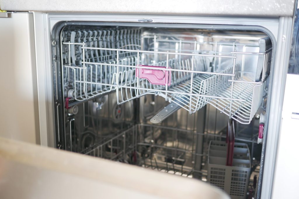 The empty wire baskets of a dishwasher seen through its open door