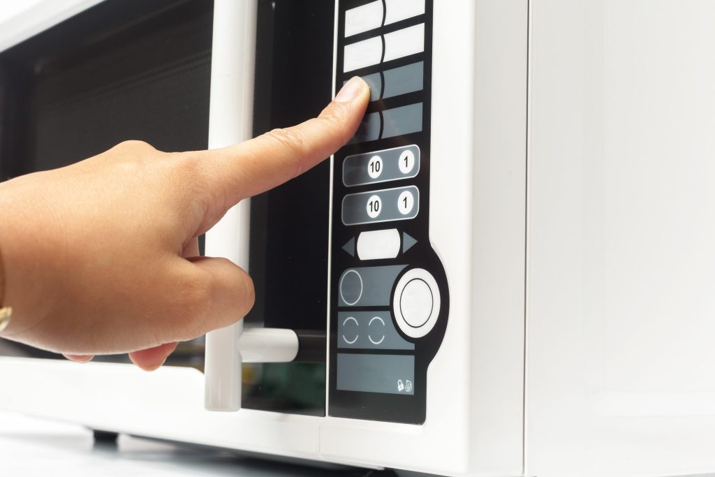 A finger pressing one of the membrane keys on a microwave keypad