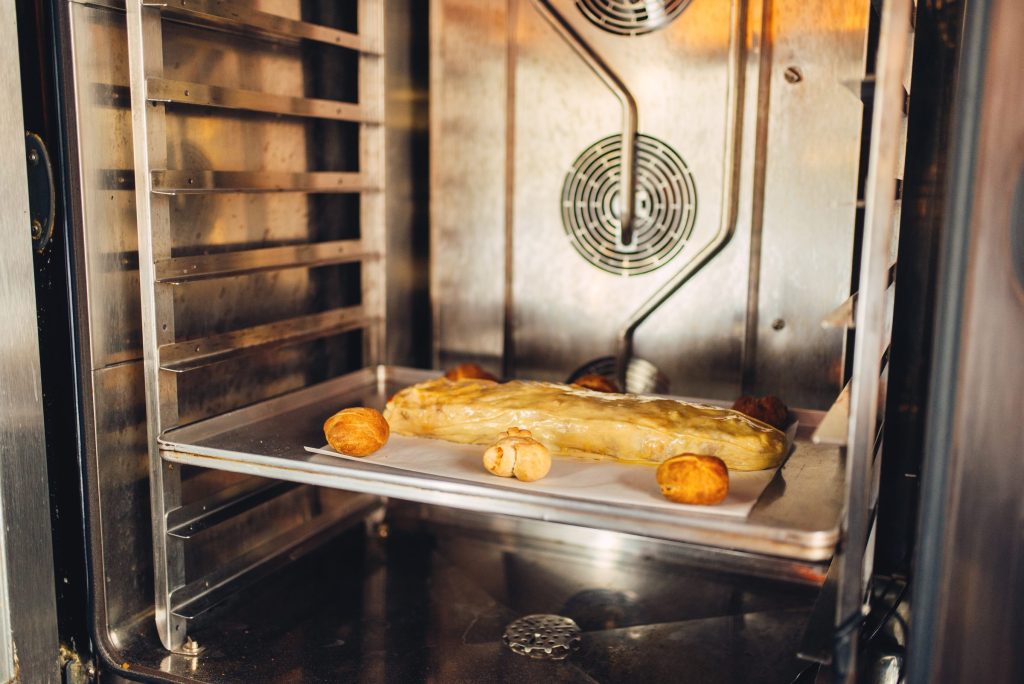 Food on a tray on the middle rack of a lit oven cavity