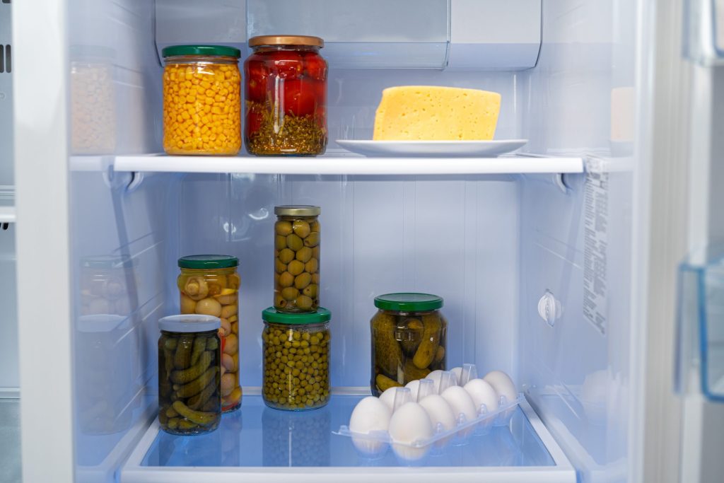 Jars, eggs and preserves on the shelves of an open refrigerator
