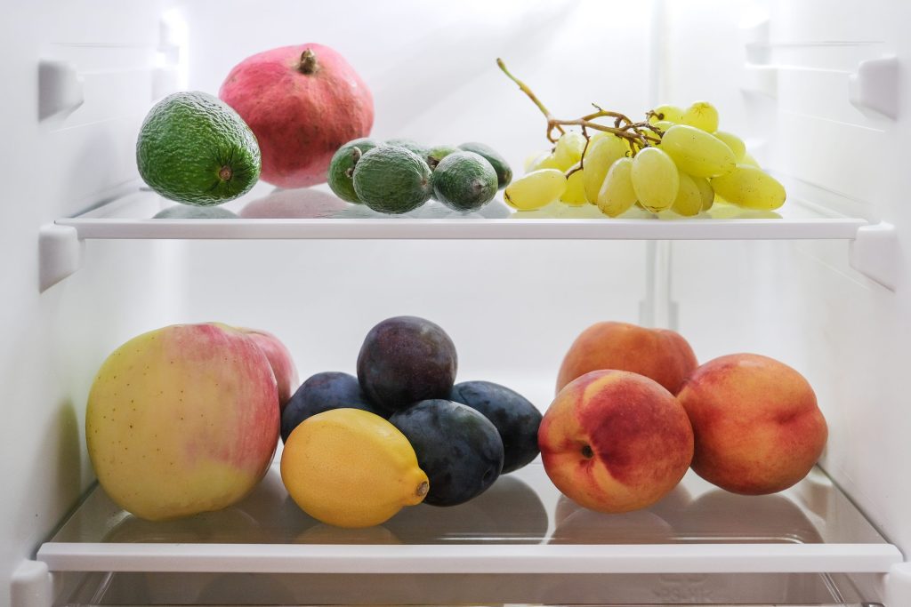 Fruit resting on two glass shelves inside a refrigerator
