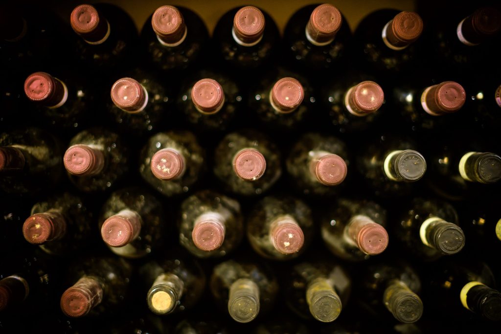Rows of bottles resting on the lit racks of a wine cabinet