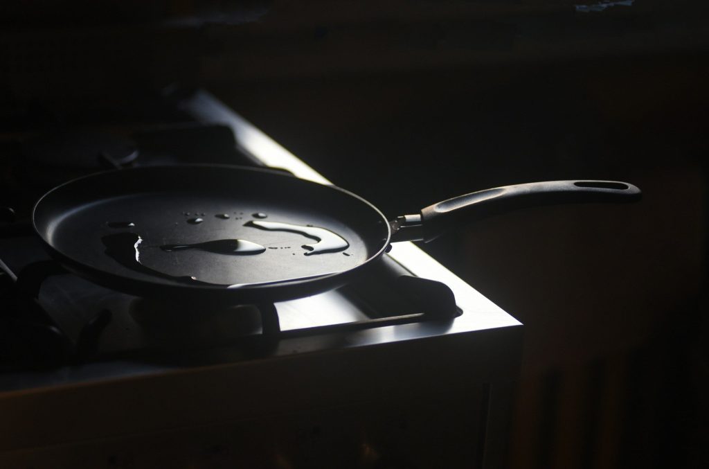 A frying pan on a dark induction surface in low kitchen light